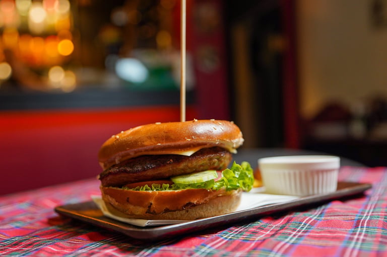Gourmet burger with lettuce and sauce on a plate with sauce cup in a modern restaurant setting