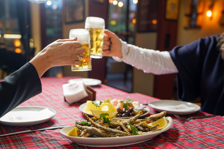 Two people toasting beer glasses at dinner